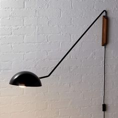 a black floor lamp against a white brick wall