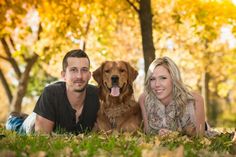 a man and woman laying in the grass with their dog, who is looking at the camera