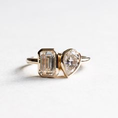 Emerald cut moissanite with pear moissanite on this you and me ring. Metal: 14k Gold Stone Shape: Emerald cut Stone Size:  5mm x 7mm Emerald Cut Weight: 1.01 CTW Stone Shape: Pear cut Stone Size: 5mm x 7mm Pear Weight: 0.45 CTW  Color: DEF Forever One Charles and Colvard Band Width: Approx 1.8mm band width  This ring is customizable with your choice of gemstones. Please contact us for custom work. SKU:0015 Toi Et Moi Ring Bezel, Toi Et Moi Bezel Ring, Bezel Toi Et Moi Ring, Cute Engagement Rings, Bezel Engagement Ring, Future Engagement Rings, Emerald Cut Moissanite, Gold Rings Fashion, Bezel Ring