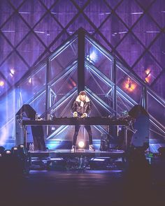 a woman standing on top of a stage in front of a piano and microphones