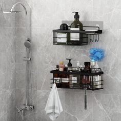 two black shelves with bottles and soaps on them in the corner of a bathroom