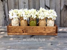 four jars with flowers in them sitting on a table