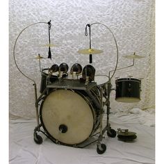 a drum set with three drums and two cymbals sitting on a white sheet