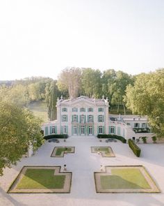 an aerial view of a large white house surrounded by trees and lawns with hedges