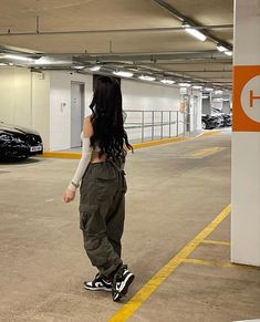 a woman standing in a parking garage next to a black car and holding her hand on her hip