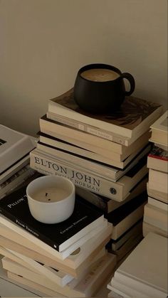 a stack of books and a candle on top of each other next to a cup