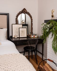 a bedroom with a bed, desk and mirror on the wall next to each other