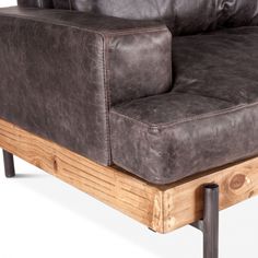 a brown leather couch sitting on top of a wooden frame