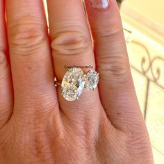 a woman's hand with two diamond rings on top of her finger and the ring has three diamonds in it