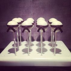 four cake pops with white frosting and black bows on them sitting on a tray