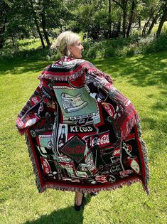 a woman is standing in the grass with a blanket on her back