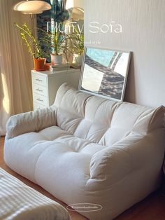 a white futon sofa sitting on top of a hard wood floor next to a window