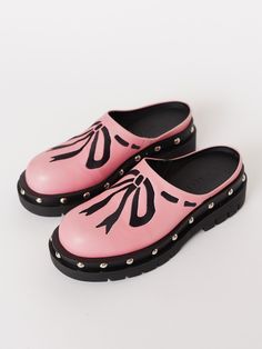 Plumbers are big fans of clogs, wonder why…Your new summer shoe has finally arrived! In pink, these slip-on clog shoes are made from 100% vegan leather with a contrasting cleated rubber sole that has a slight heel, and stud detailing all the way around. They have a side gusset which helps give ease and comfortability to the wear of the shoe. Across the body of the shoe is an embroidered bow detailing in a contrasting black. Spring Slip-on Clogs With Studded Rubber Outsoles, Spring Slip-on Clogs With Rubber Heel Cap, Pink Round Toe Clogs For Spring, Trendy Closed Toe Clogs With Rubber Sole, Trendy Flat Platform Clogs, Pink Slip-ons With Rubber Sole, Trendy Slip-on Clogs With Round Toe, Trendy Slip-on Clogs With Lug Sole, Trendy Clogs With Lug Sole And Round Toe