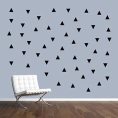 a chair sitting on top of a hard wood floor next to a wall with black triangles