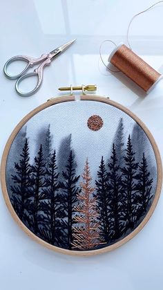 an embroidery project with scissors, thread and spools on a white table top