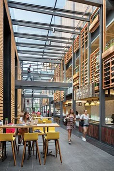 people are sitting at tables in the middle of an open air dining area with wood and glass walls