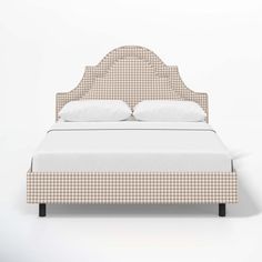 an upholstered bed with white pillows and checkered headboard, against a wall