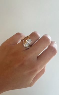 a person's hand holding a ring with a diamond in the middle and a gold band around it