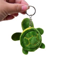 a hand holding a keychain with a green turtle on it