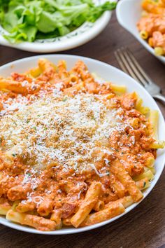 pasta with sauce and parmesan cheese in a white bowl on a wooden table