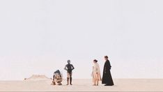 three people standing in the sand near one another