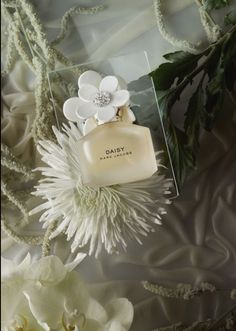 a bottle of perfume sitting on top of a white flower