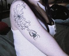 a woman with a spider web tattoo on her arm and shoulder, sitting in bed