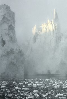 an iceberg in the middle of water with snow on it's sides and ice floes floating around