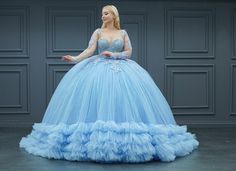 a woman in a blue ball gown is standing with her hands out to the side