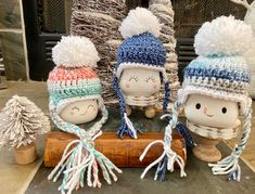 three knitted dolls are sitting next to each other on a piece of driftwood