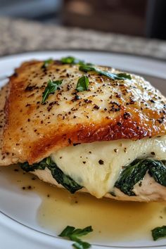 a white plate topped with fish covered in cheese and spinach