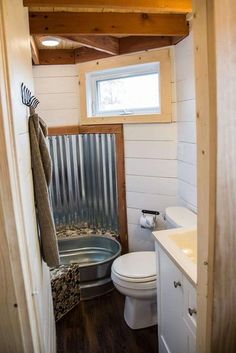 a bathroom with a tub, sink and toilet in it's stall area next to a window