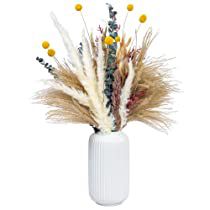 a white vase filled with dry grass and yellow flowers