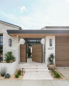 the front entrance to a modern home with wooden doors