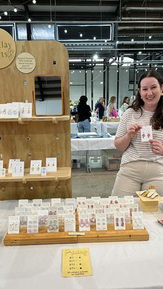 a woman standing in front of a table with cards on it and other items for sale