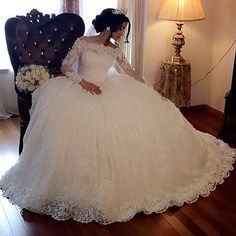 a woman in a white wedding dress sitting on a chair with her hands behind her back