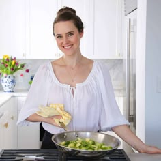 a woman in a white blouse holding a pan with food on it