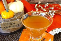 a glass filled with liquid sitting on top of a table next to pumpkins and other decorations