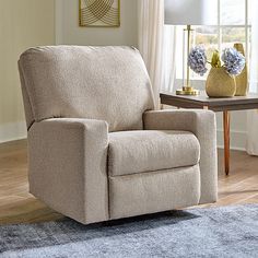 a beige recliner sitting on top of a wooden floor next to a table with vases