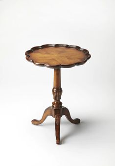 a small wooden table with an ornate design on the top and bottom, sitting against a white background