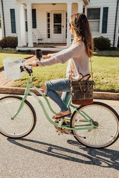 a woman riding on the back of a green bike with a bucket in her hand