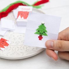 someone is holding up some christmas cards on a plate with red and green decorations around them