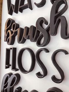 the letters are made out of wood and have black paint on them, including one that says wash brush floss