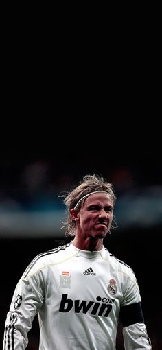 a man with long hair standing in front of a soccer ball