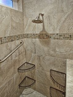 a walk in shower with tiled walls and flooring next to a window above it