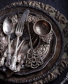 an ornate silver plate with utensils and spoons on it