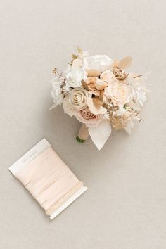 a bridal bouquet and notepad sitting next to each other on a white surface