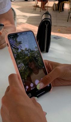 a person is taking a photo on their cell phone at an outdoor table with other people