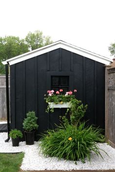 a black shed with potted plants next to it