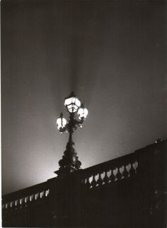 a black and white photo of a street light on a bridge at night with the sky in the background